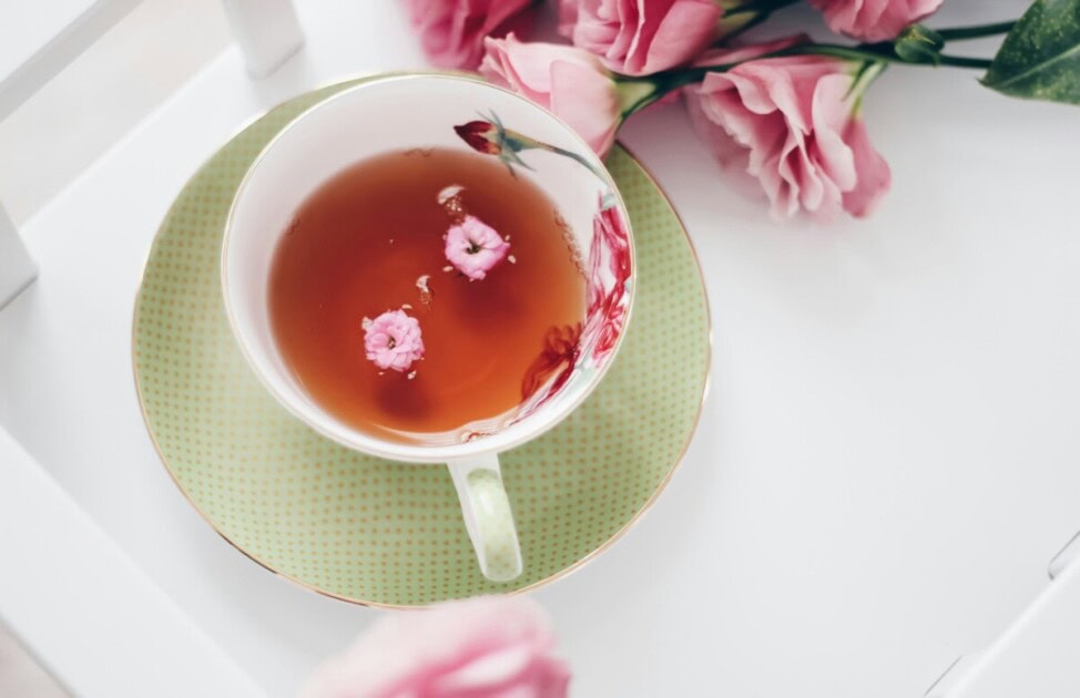 Flowers sitting next to a tea cup with tea in it