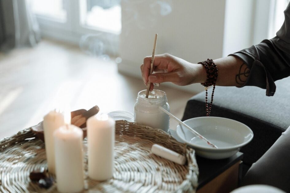 someone uses sage while candles burn to manifest their dream home