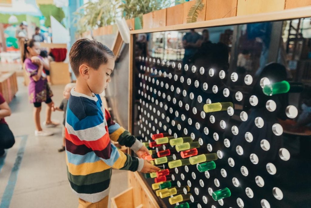 Kid playing with an exhibit at the San Diego children's Discovery Museum during summer camp