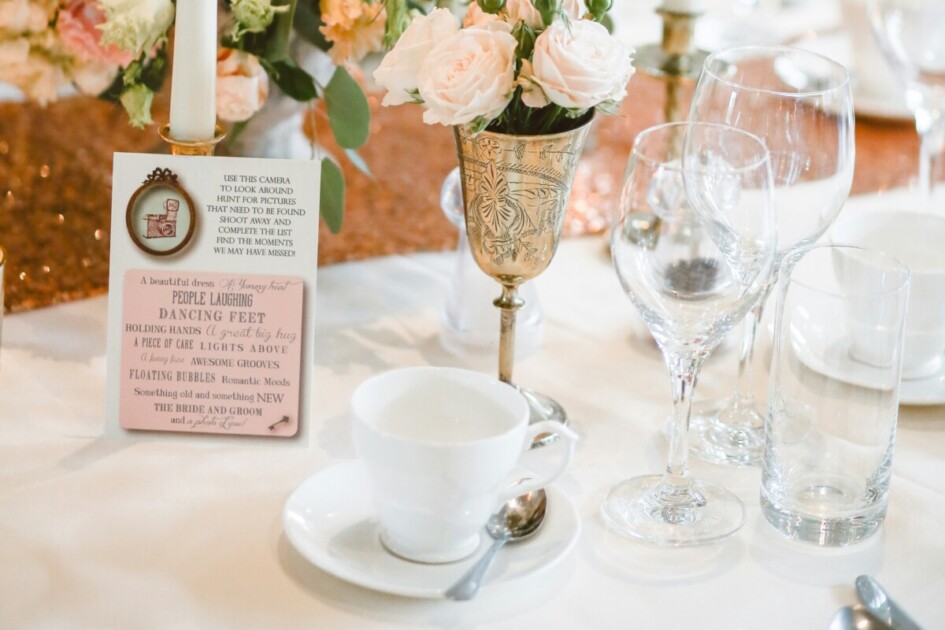 a cute customizable sign sits on a table with pink flowers and empty glasses at a home bridal shower--a great idea for decor in Redfin's home bridal shower article