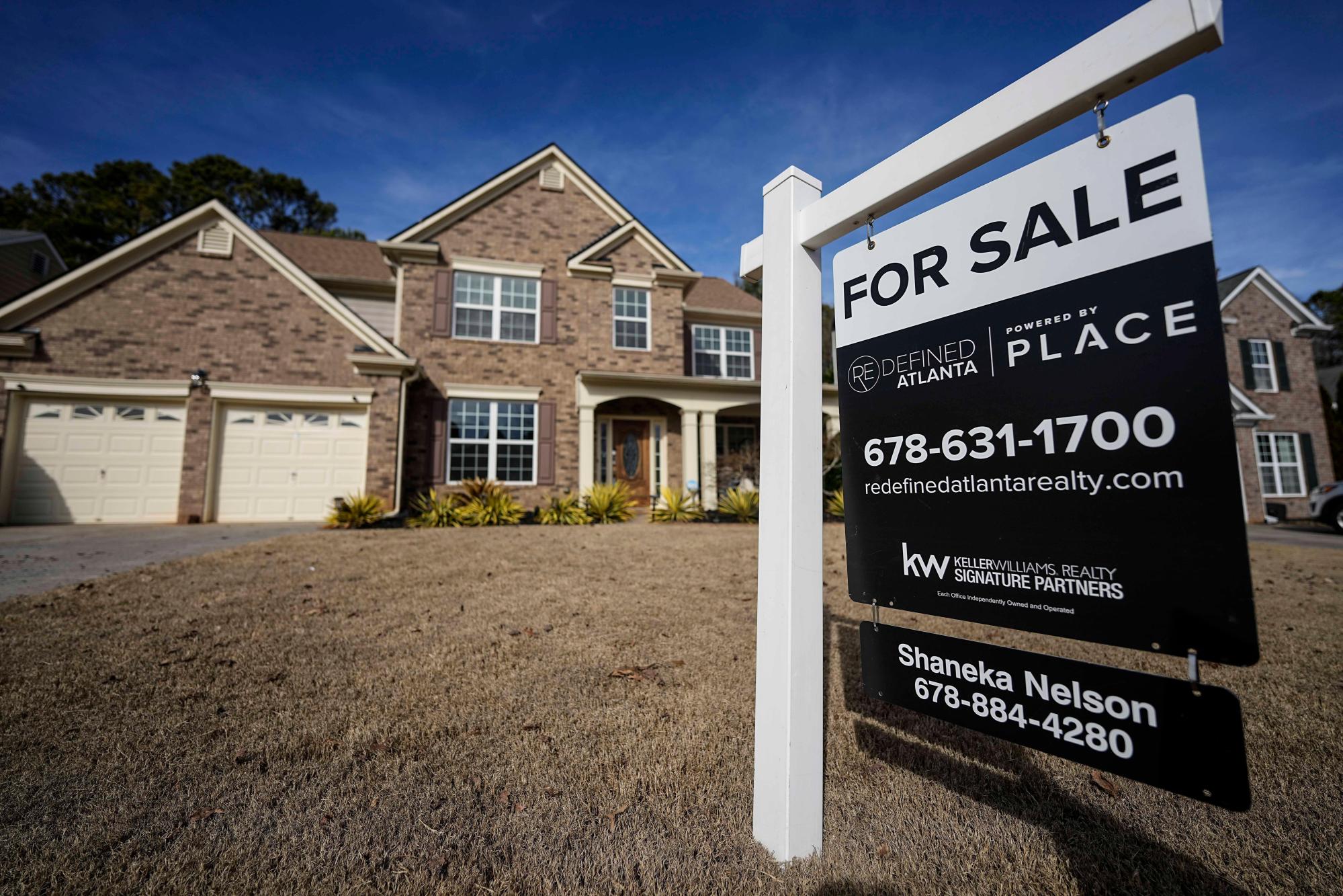 A sign announcing a home for sale is posted outside a home