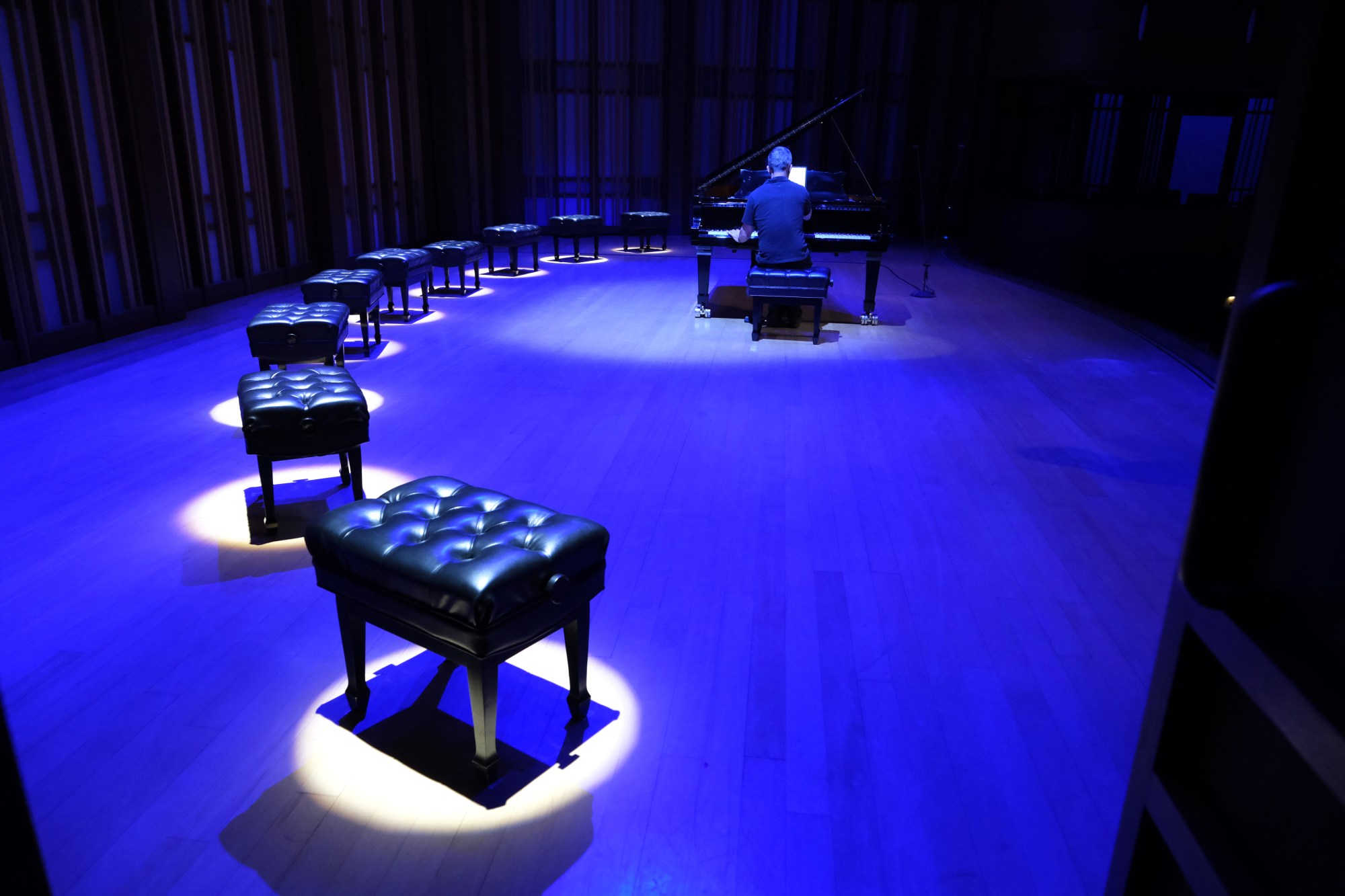 Nine piano benches, one for each pianist, decorate the stage during "The Glass Menagerie" concert on Saturday, July 26, at the Conrad Prebys Performing Arts Center in La Jolla. The concert, which featured nine pianists performing Philip Glass's Twenty Etudes, was presented during opening weekend of La Jolla Music Society's SummerFest 2025. (Ken Jacques)