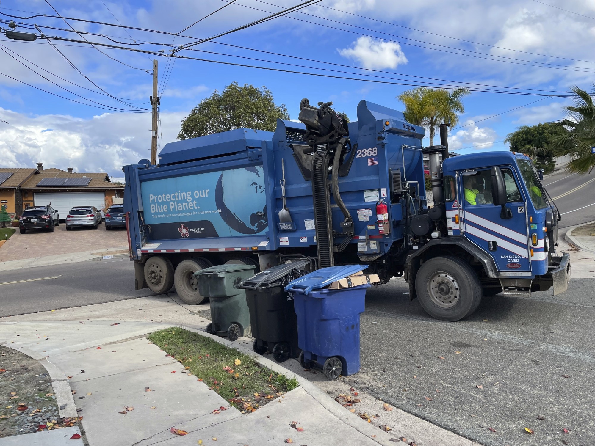 A "blue crew" from Republic Services picks up trash in front of a Chula Vista home. (Gary Warth / The San Diego Union-Tribune)