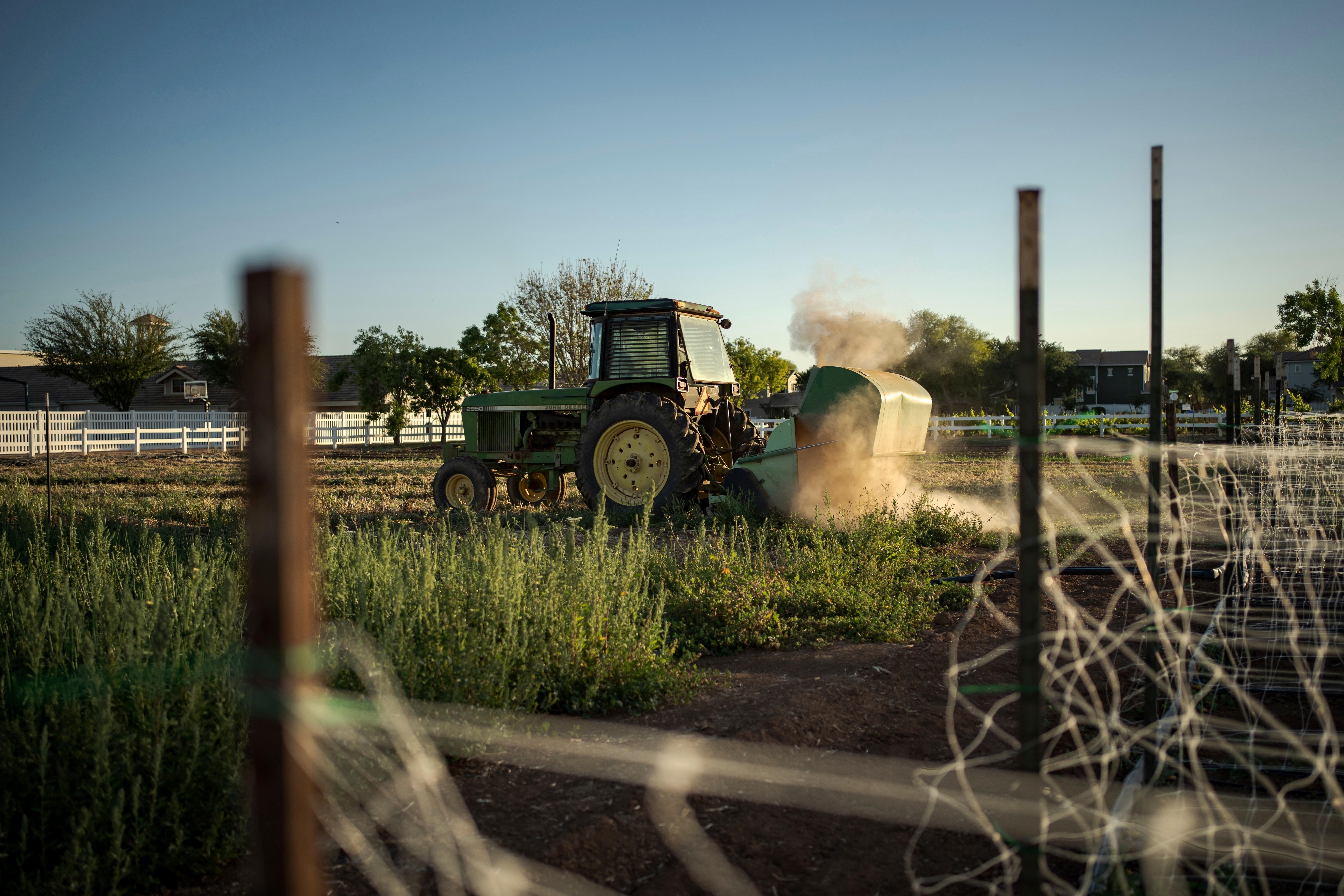 A tractor clears farmland in Agritopia, a community nestled around...