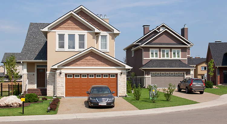 Front view of two suburban houses with cars parked in their respective garage