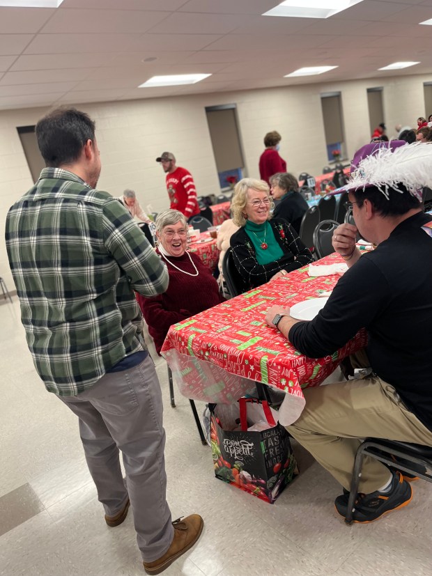 Man entertaining dinner attendees at long table