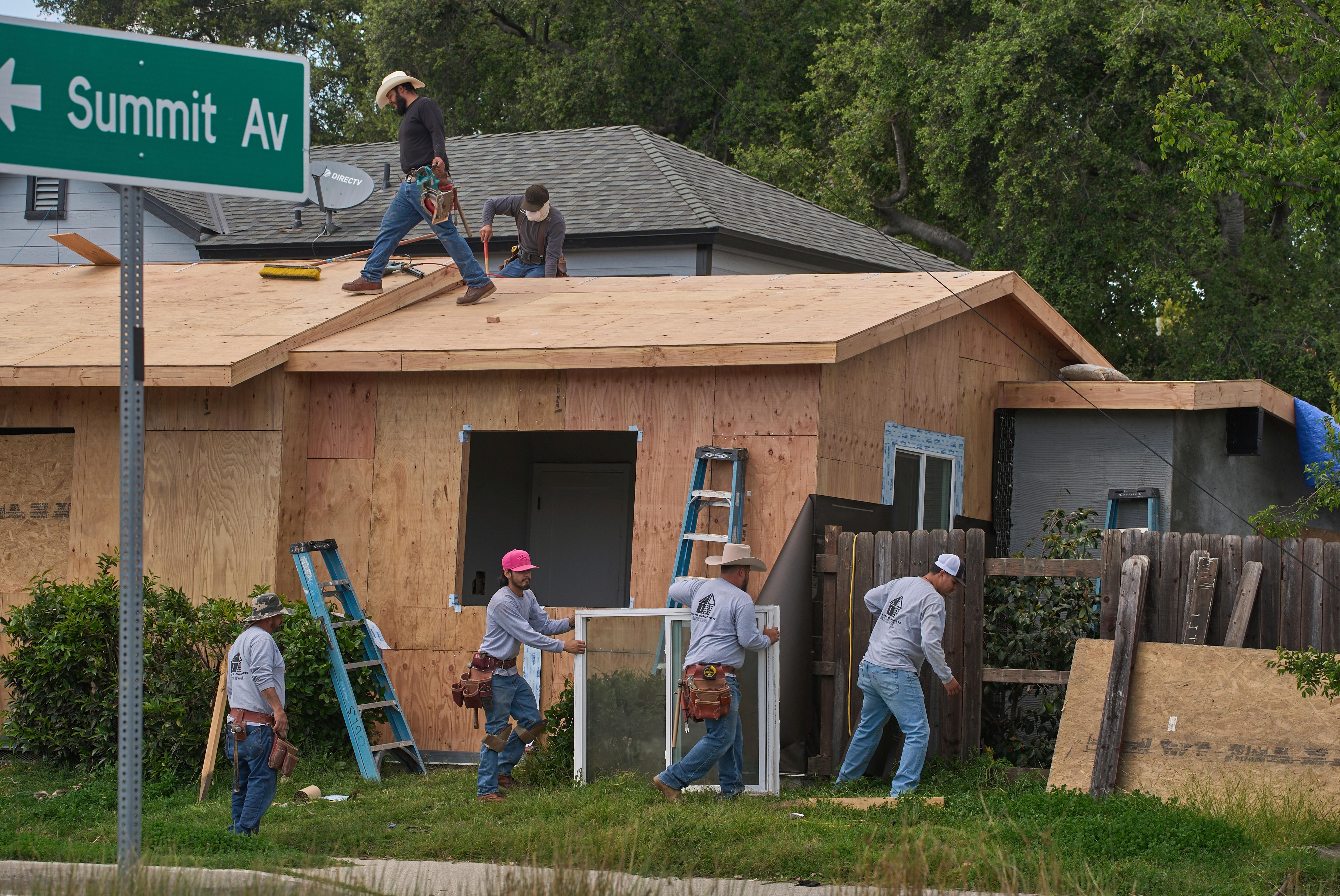 Construction crews build a new roof and windows on a...