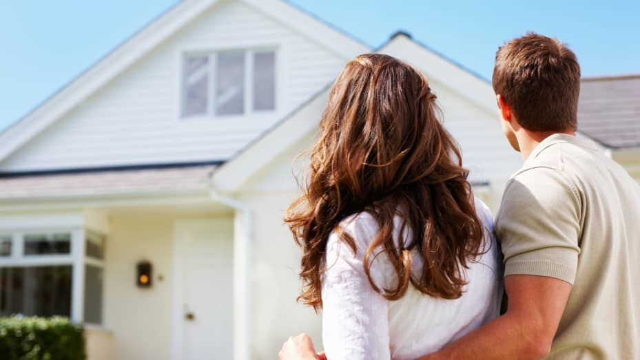 Rear view of a couple standing in front of their new house